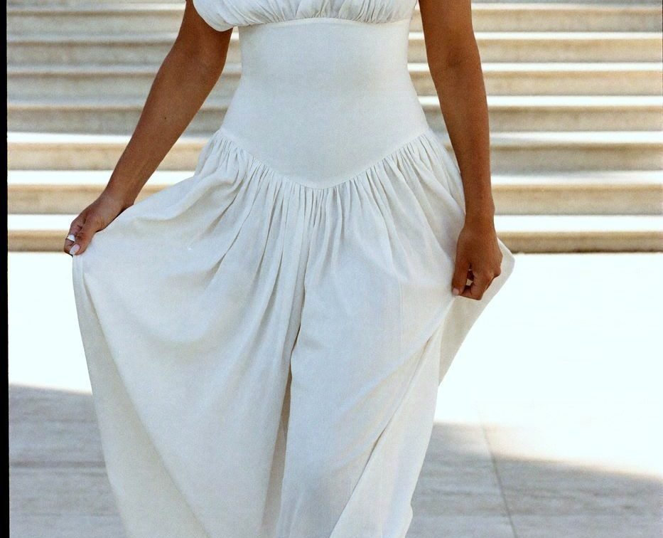 A woman in a white summer dress walking barefoot